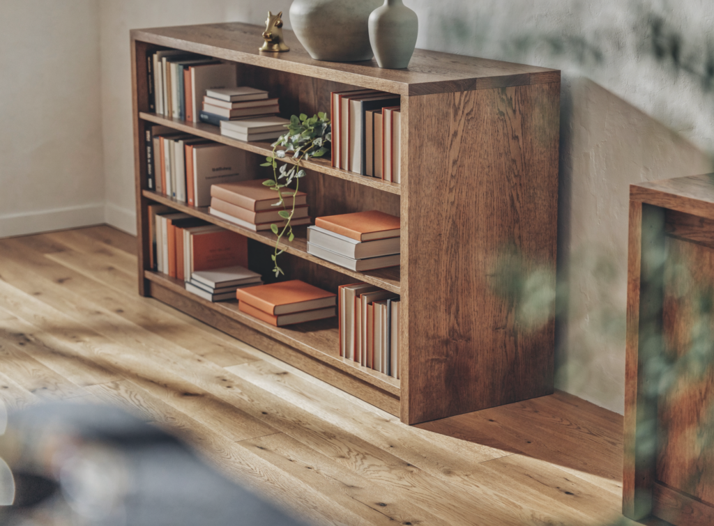 Eiken Boekenkast Met Boeken En Decoratie Eiken Boekenkast Met Open Vakken Vol Boeken, Vazen En Een Plant In Een Warme Woonkamer